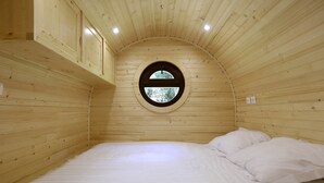 A cozy, circular wooden room with a bed and a window. - Domaine de Marguerite (Janvry)