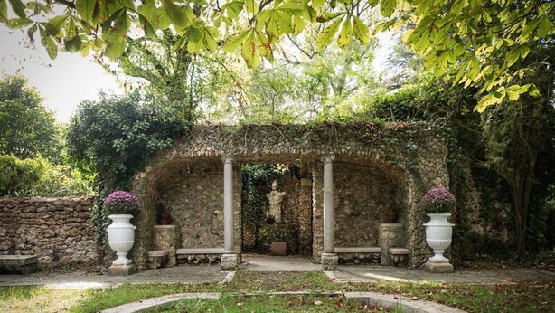 A stone archway with a statue, surrounded by greenery and stone walls. - Domaine de Marguerite (Janvry)