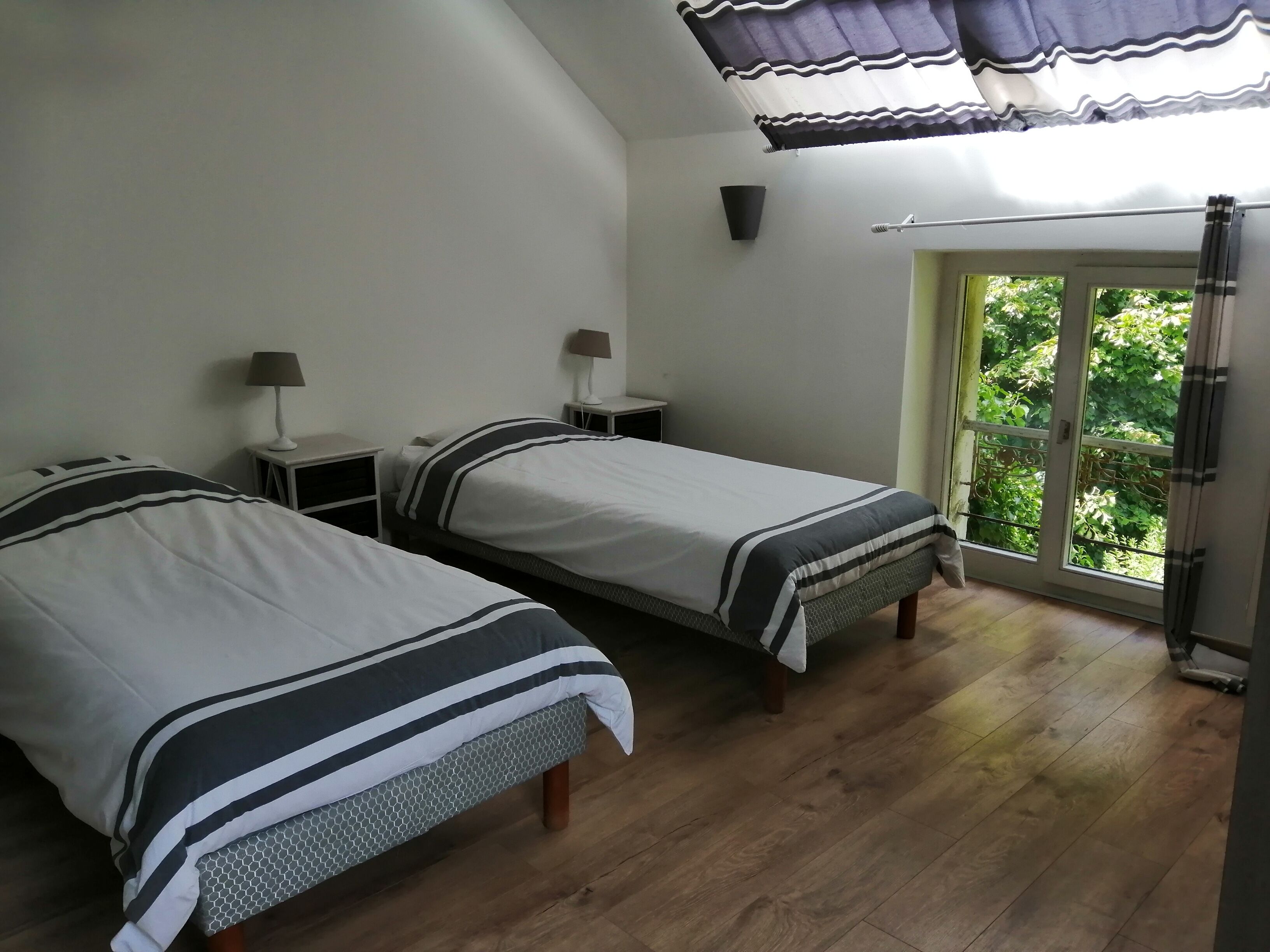 Un dormitorio con dos camas, una ventana con vistas a zonas verdes y un ventilador de techo.