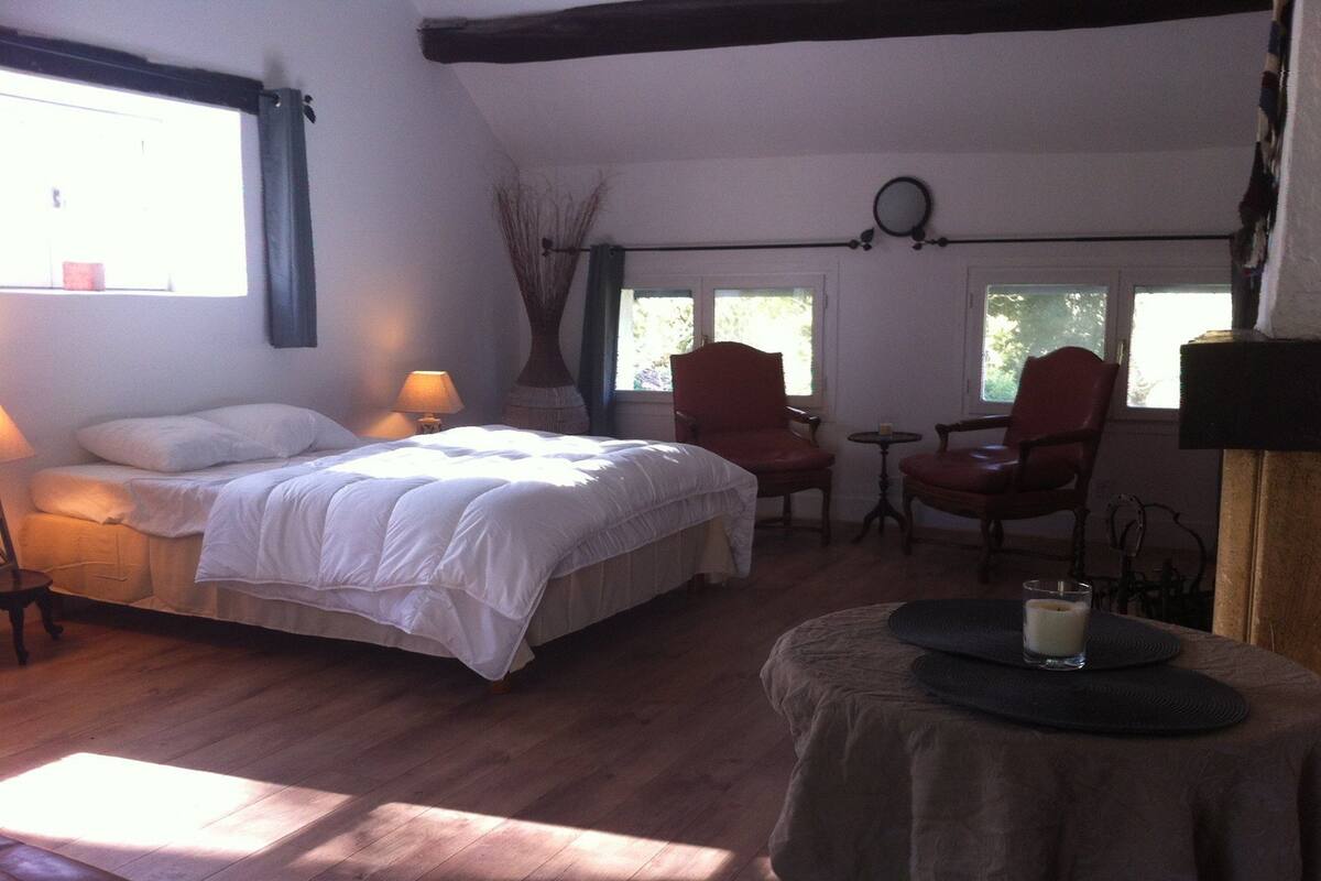 Un dormitorio con cama, dos sillas, una mesita y una ventana.
