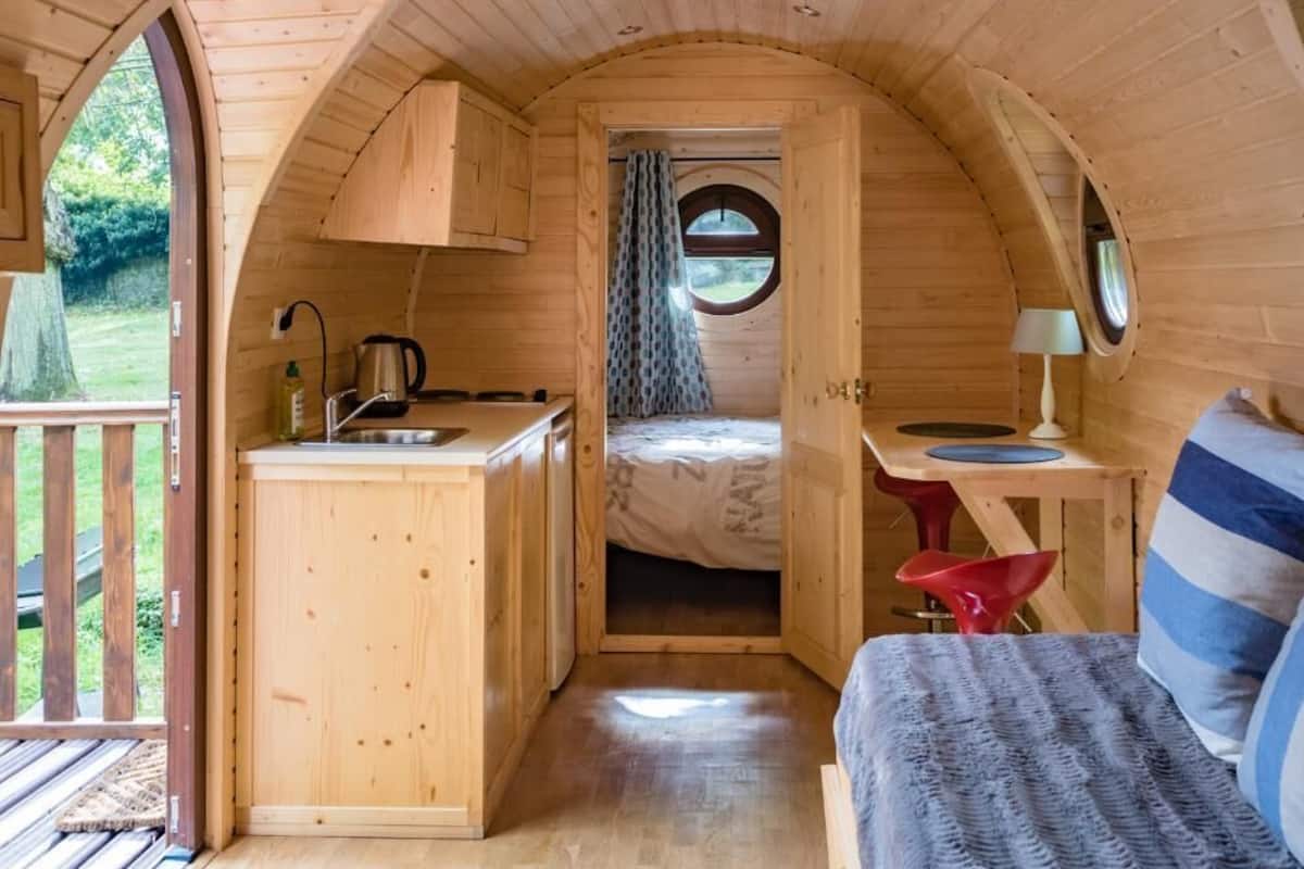 Un interior acogedor de madera, con cocina, cama y una pequeña mesa.