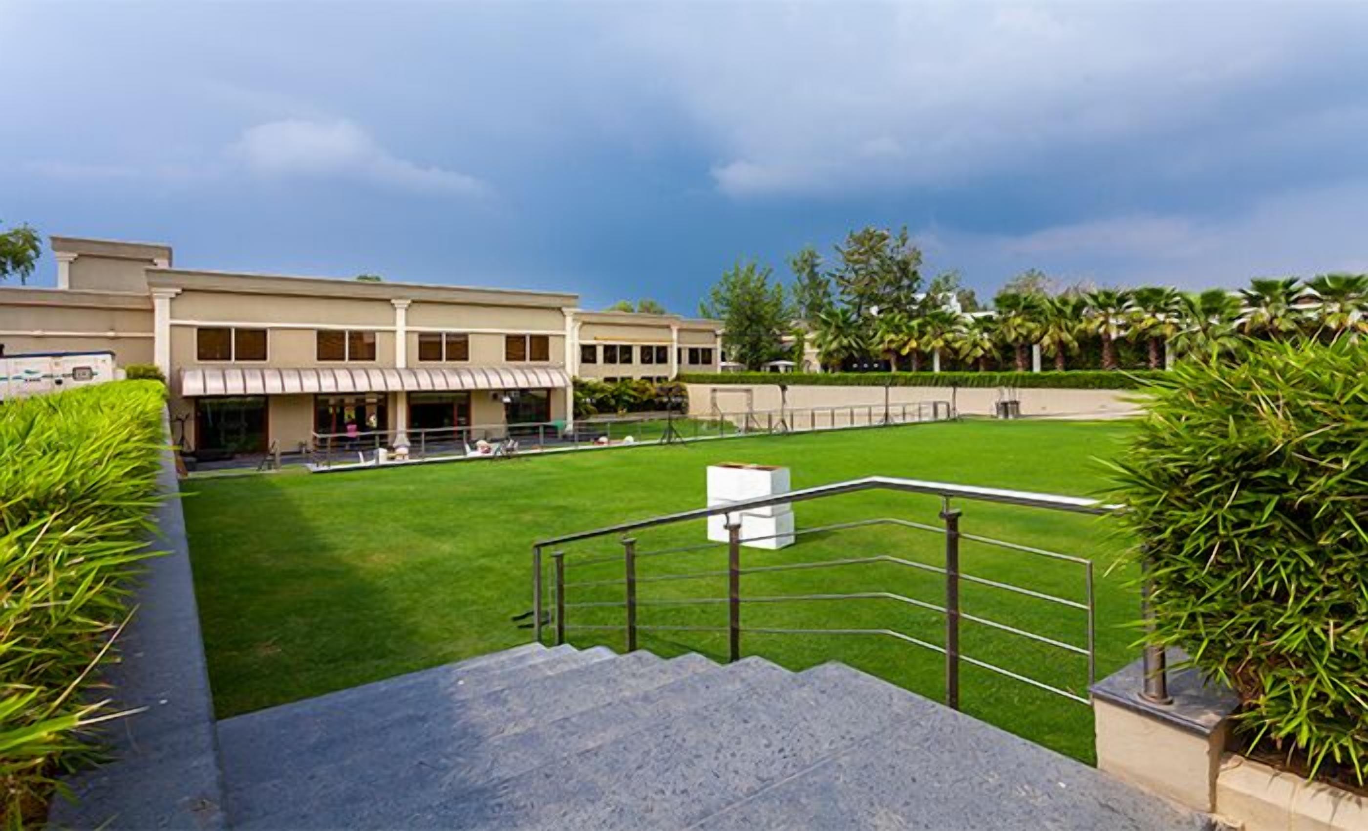 A building with a flat roof, a covered walkway, and a grassy courtyard.