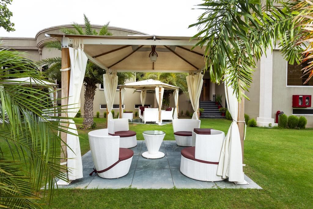 An outdoor seating area with white wicker furniture and a covered section.