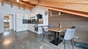 Una cocina moderna con armarios blancos, una estufa de acero inoxidable y una mesa de comedor de madera con dos sillas.