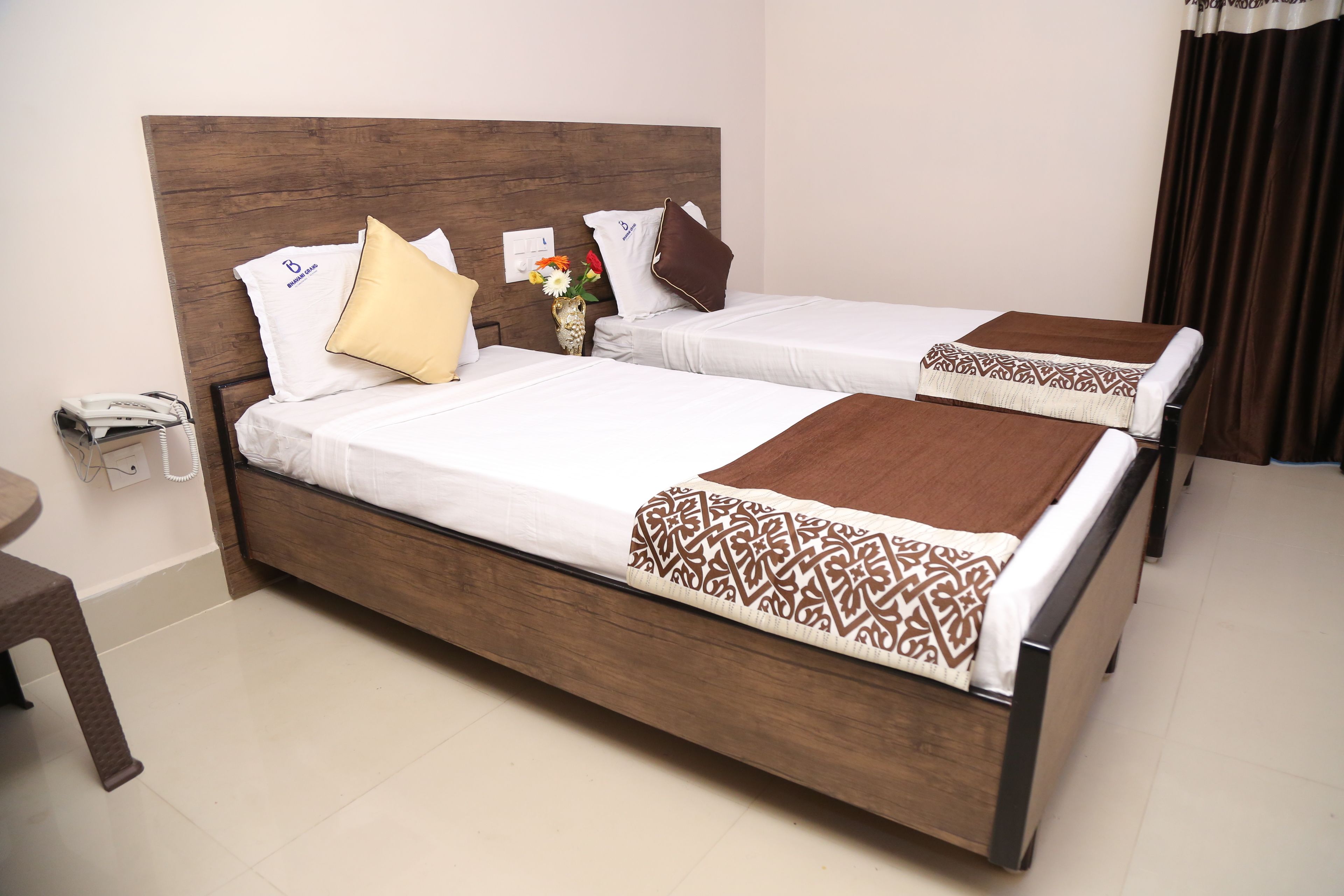 A hotel room with two single beds, a wooden headboard, a telephone, and a small table.