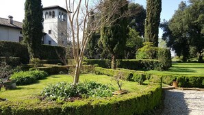 A formal garden with neatly trimmed hedges, a variety of trees, and a gravel path. - Villa di Tissano (Santa Maria la Longa)