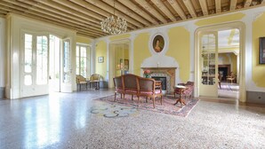 A spacious room with a high wooden ceiling, a fireplace, and a large window. - Villa di Tissano (Santa Maria la Longa)