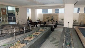 Un'ampia hall con un'area salotto centrale, una scala e una fontana decorativa.