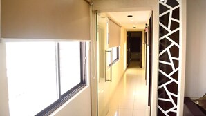 A hotel corridor with a glass door, a beige wall, and a decorative white panel.