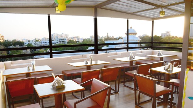 A restaurant with multiple tables and chairs, large windows offering a city view, and a modern interior design.
