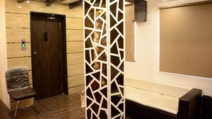 A modern interior with a wooden door, a white partition, a cushioned bench, and a digital display.