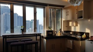 A kitchen with a large window, wooden cabinets, a microwave, and a sink.
