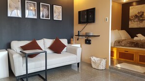 A modern living room with a white sofa, brown cushions, a TV mounted on the wall, a small table, and a basket.