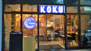 A KOKU restaurant with a neon sign, a VISA acceptance sign, and a glass entrance.