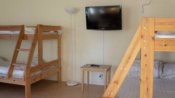 Ein Zimmer mit zwei Etagenbetten, einem an der Wand befestigten Fernseher und einem kleinen Tisch mit einer Fernbedienung.