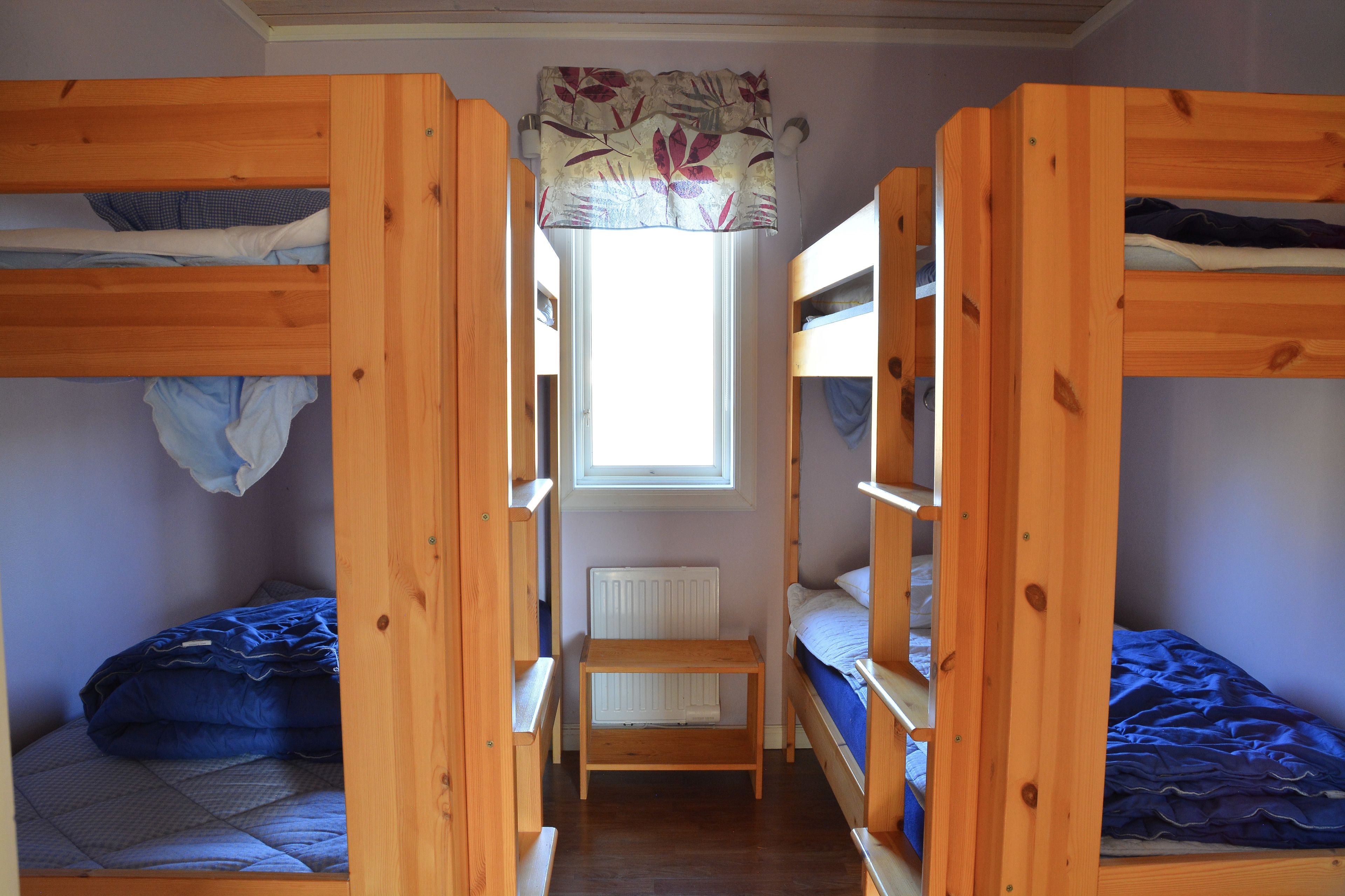 A room with bunk beds, a window with a curtain, and a radiator.