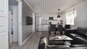 Eine moderne Küche mit weißen Schränken, einer Mikrowelle und einem Essbereich mit Tisch und Stühlen.