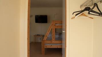 Una habitación con una cama litera, un televisor montado en la pared y una mesita.