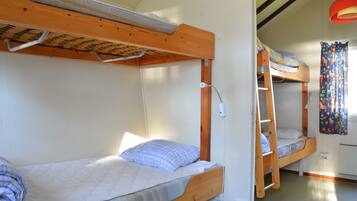 A bunk bed room with a wooden headboard, a mattress, and a pillow.