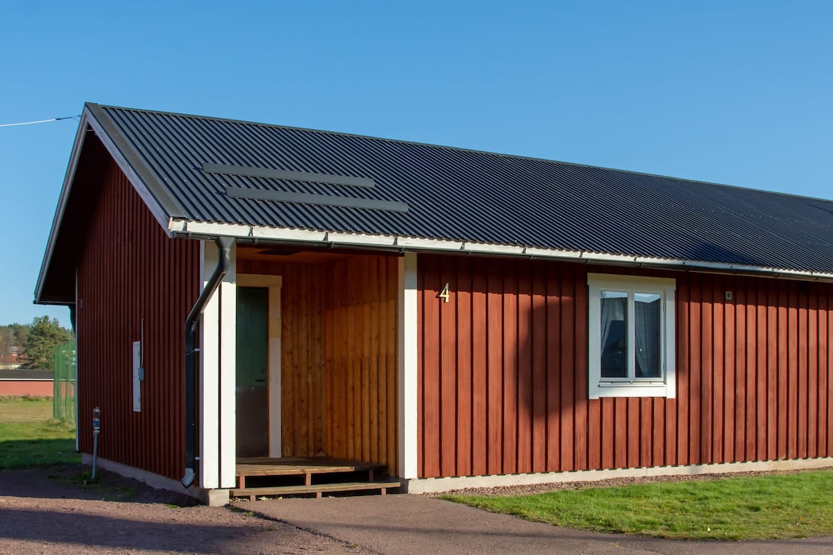 A red building with a metal roof and a wooden door.