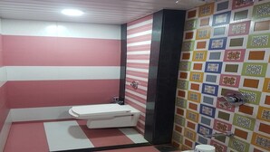 Un baño con inodoro blanco, paredes rosa y blanco y una pared de azulejos coloridos.