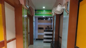 Un área de recepción con un cartel que dice "RECEPTION", suelo de baldosas y un ventilador en la pared.