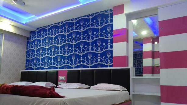 Un dormitorio con cama, pared con estampado y espejo.
