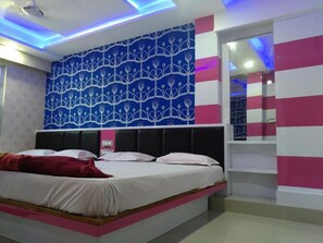 A bedroom with a bed, a patterned wall, and a mirror. - Hotel Laabh (Diu)