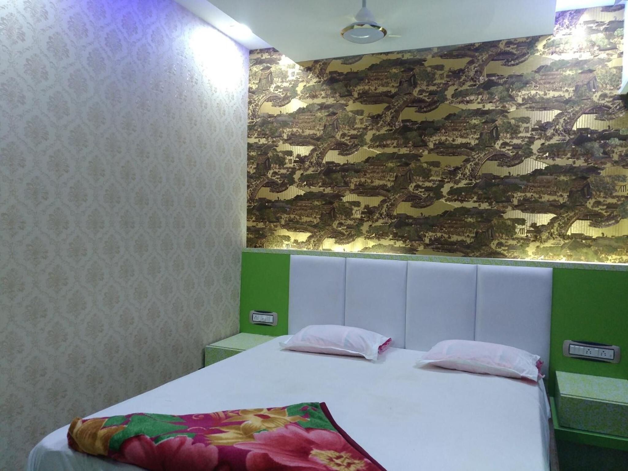Quarto de hotel com cama, cabeceira verde, papel de parede estampado e decoração na parede.