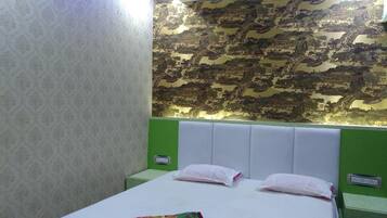 Quarto de hotel com cama, cabeceira verde, papel de parede estampado e decoração na parede.