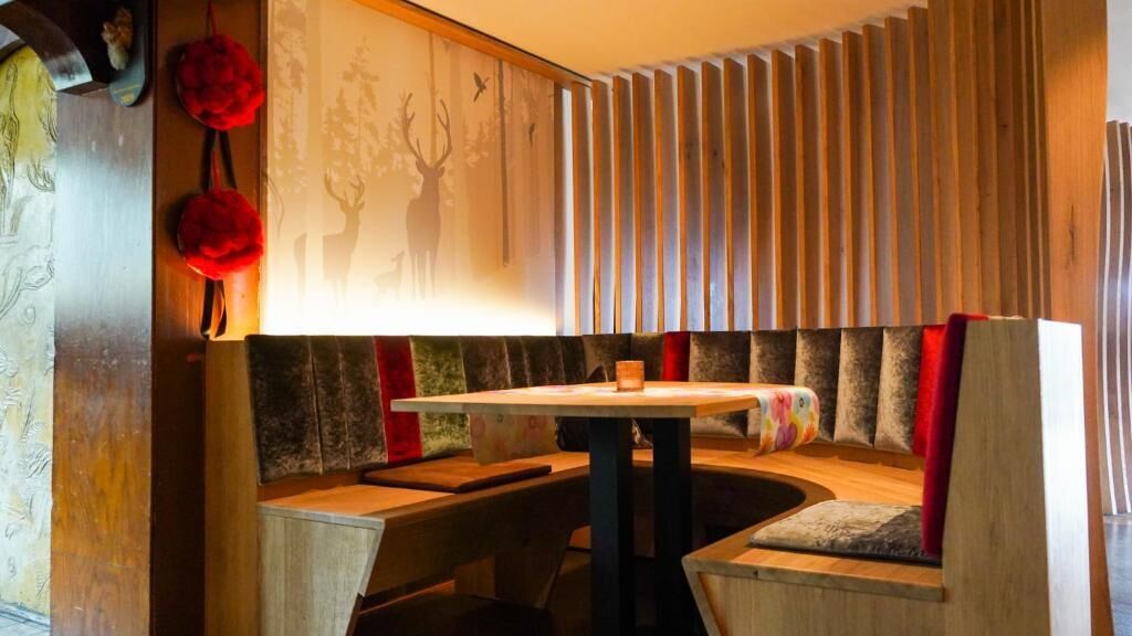 Un coin salon accueillant avec une table ronde, des bancs rembourrés et un mur composé de lattes de bois verticales.