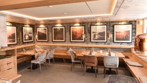 A restaurant with wooden furniture, framed pictures on the wall, and pendant lights. - Gasthof Hotel Hirschen (Schluchsee)