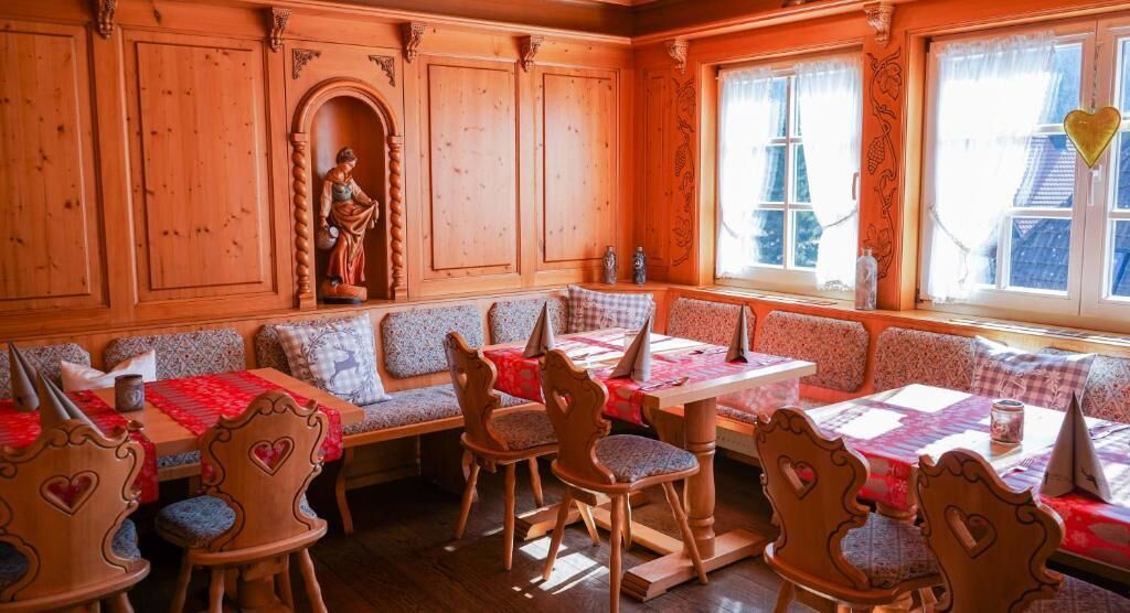 Een gezellig eetgedeelte met houten lambrisering, hartvormige stoelen en een beeld aan de muur.