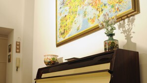 A grand piano with a decorative bowl on top, a vase with flowers, and a colorful painting on the wall. - Napolipietrasanta LT (Naples)