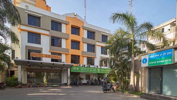 Un hotel con un letrero que dice "HOTEL KRISHNA" y un cajero automático en la planta baja.