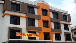 Un edificio de hotel de varios pisos con un letrero que dice 'HOTEL KRISHNA'.