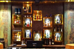 A bar area with multiple shelves displaying various liquor bottles. - Hotel Krishna (Silvassa)