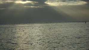 Una playa con cielo nublado y rayos de sol.