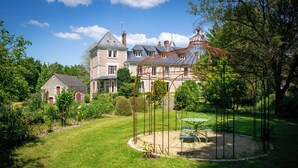Una casa grande con jardín, un porche y una mesa con sillas.