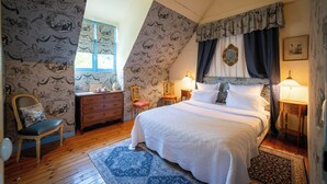 Un dormitorio con una cama grande, un aparador, una silla y una ventana.