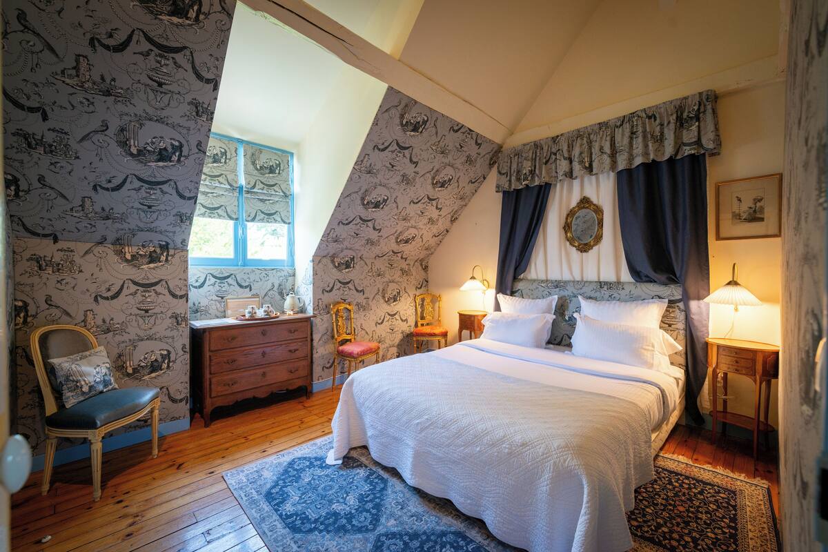 Een slaapkamer met een groot bed, een kaptafel, een stoel en een raam.