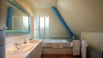 A bathroom with two sinks, a bathtub, and a large mirror.