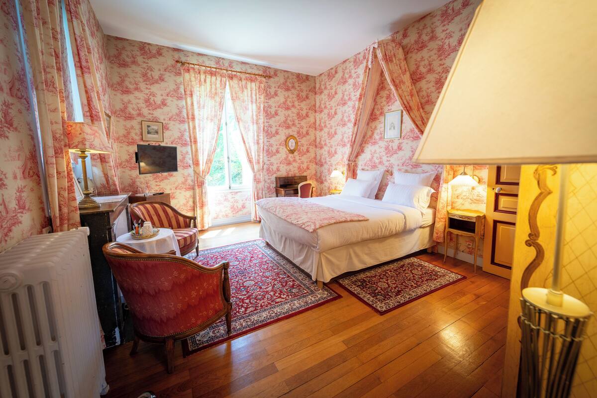 Een slaapkamer met een bed, een stoel, een bureau en een radiator.
