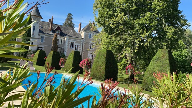 Un edificio grande e histórico con una piscina al frente.