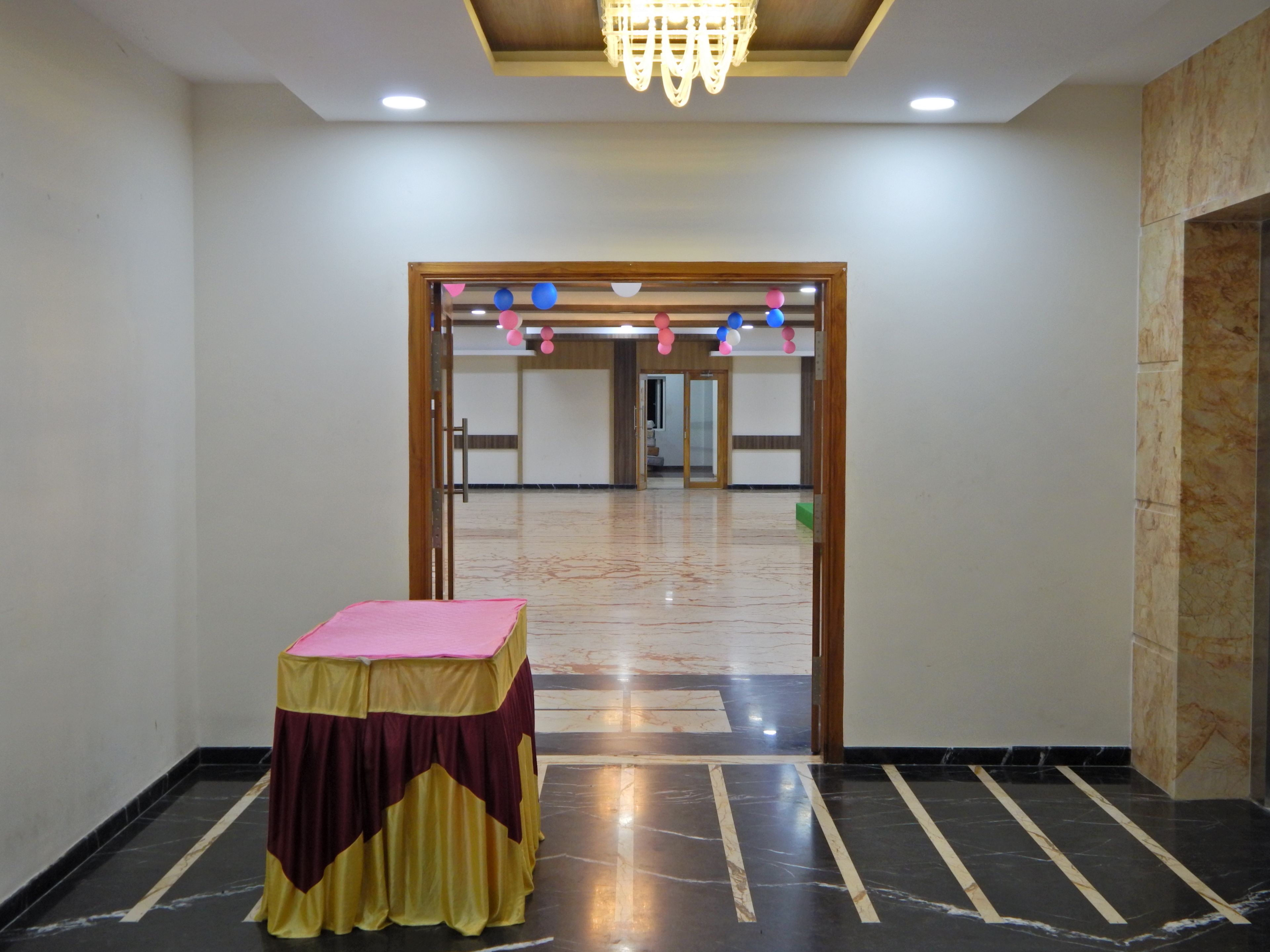 A hotel lobby with a marble floor, a reception desk, and a chandelier.