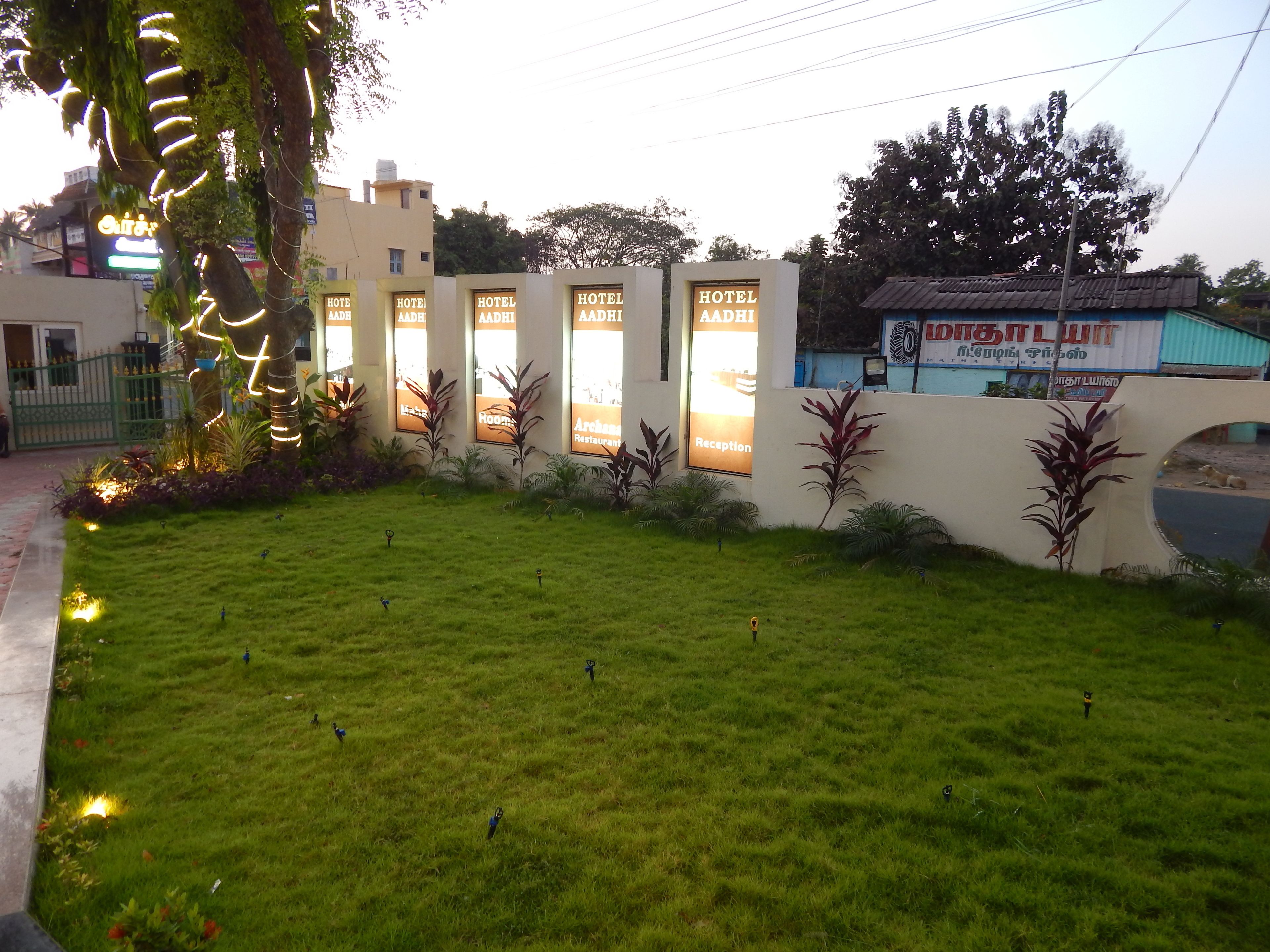 A hotel with multiple reception windows, a well-maintained lawn, and a decorative plant arrangement.