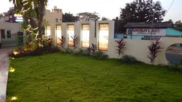 A hotel with multiple reception windows, a well-maintained lawn, and a decorative plant arrangement.