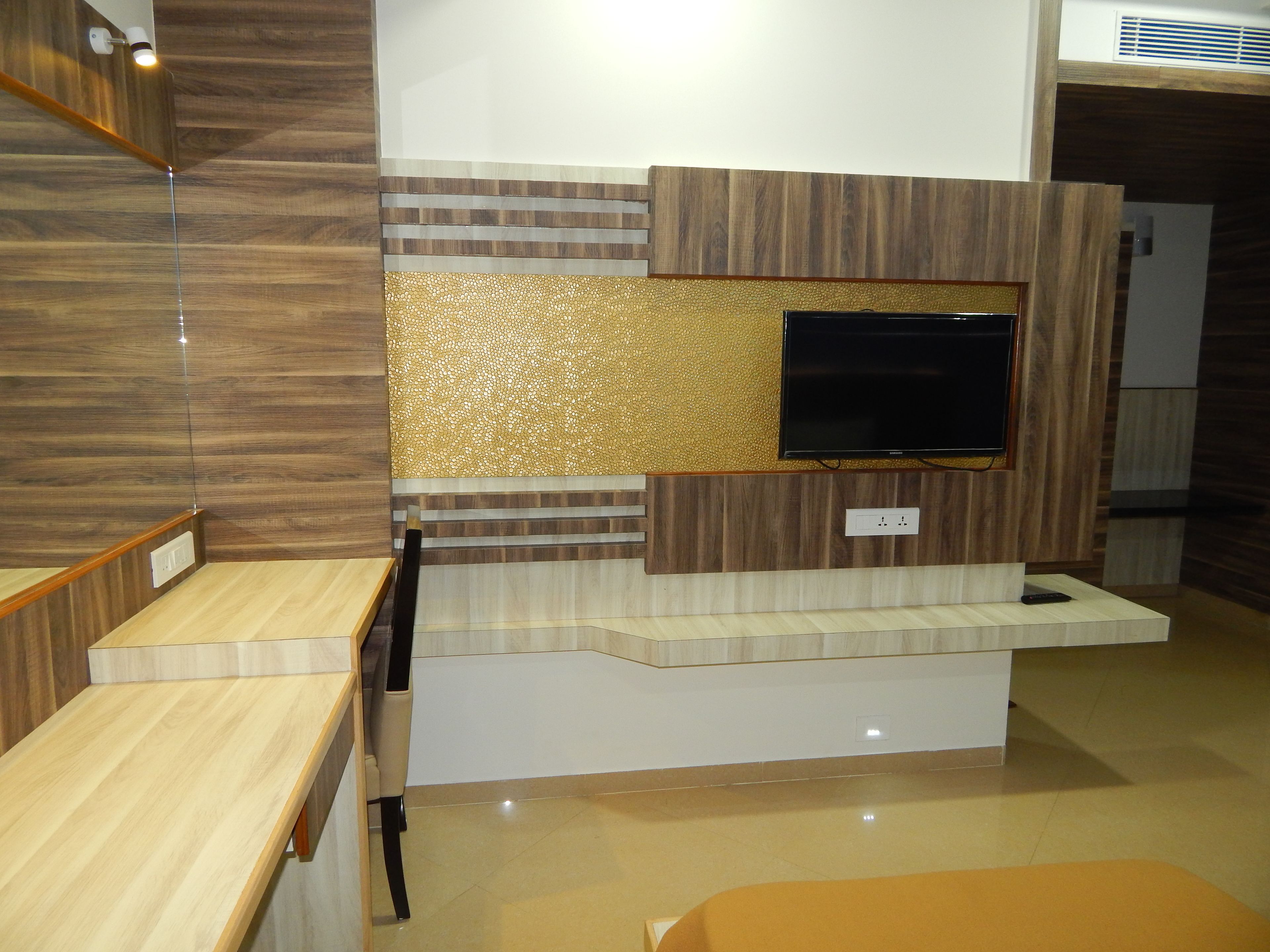 Una sala de estar moderna con televisor empotrado, paneles de madera en las paredes y piso de color claro.