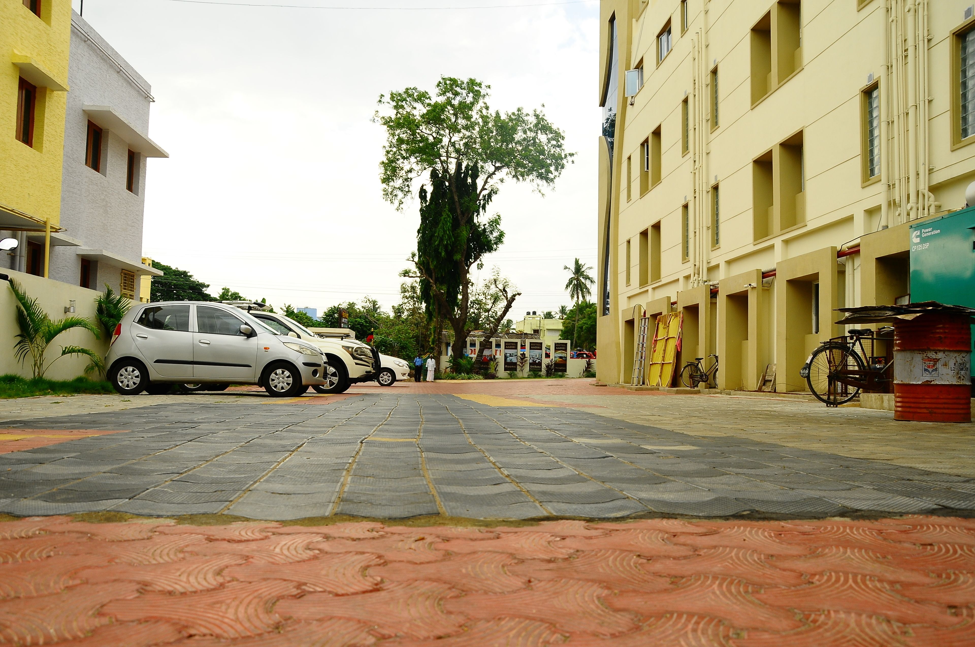 Uma rua pavimentada com carros estacionados e um edifício com fachada amarela.