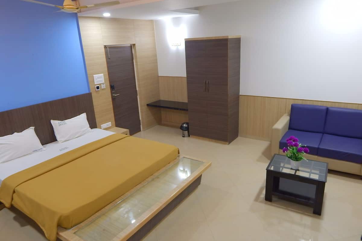 A hotel room with a bed, a sofa, a coffee table, a wardrobe, and a ceiling fan.